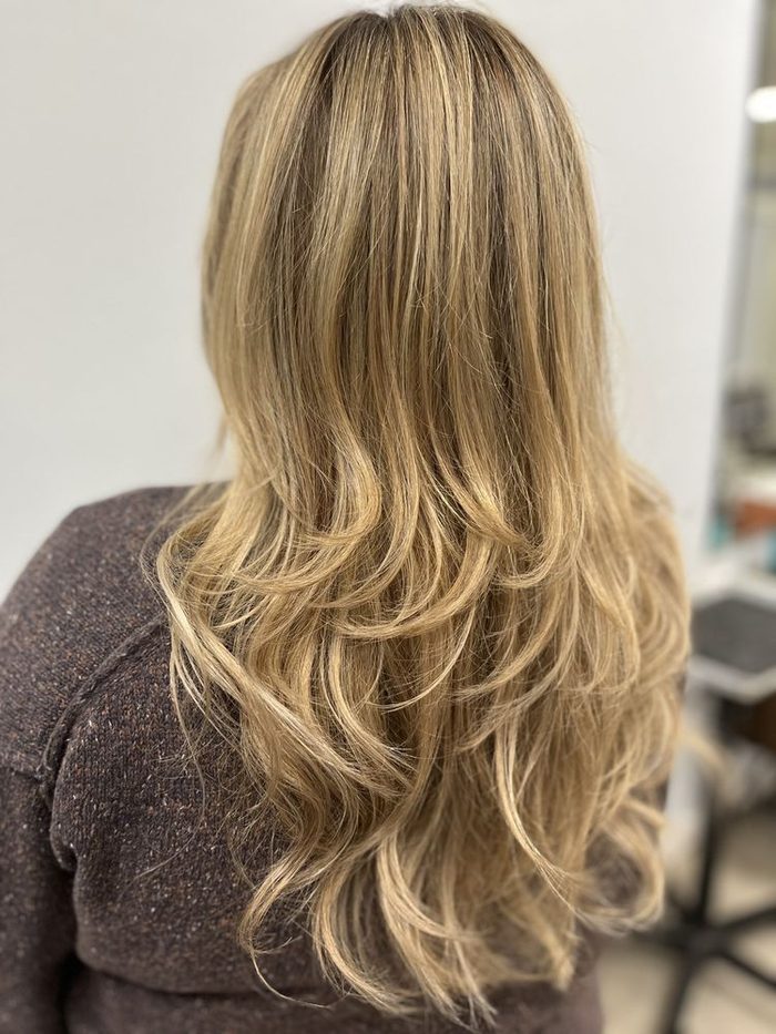 Long hair lifted to a warm blonde with soft layers.