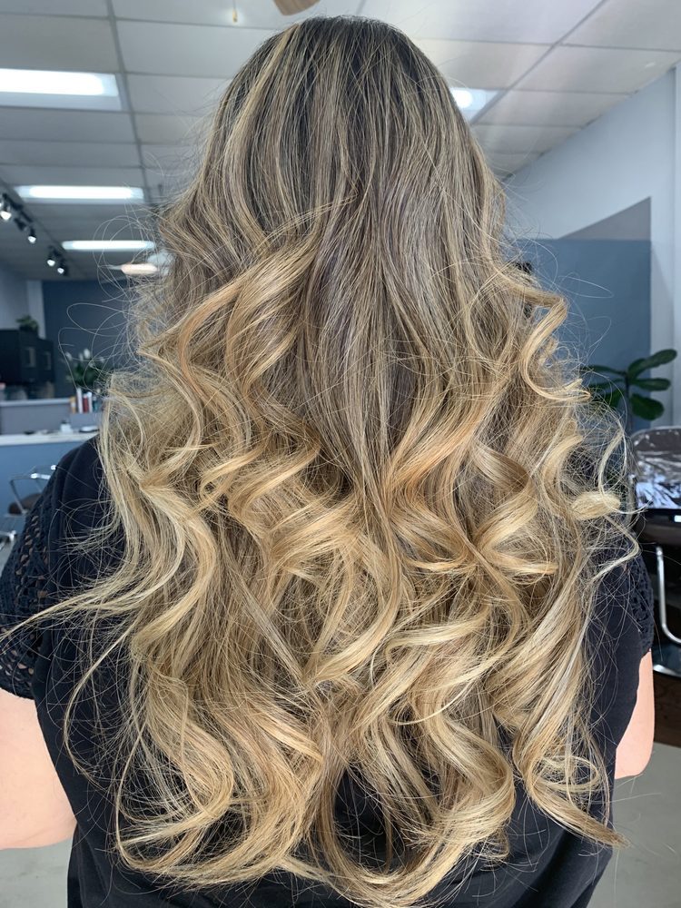 Long hair colored in a soft blonde balayage, styled in loose waves at Haute Cuts.